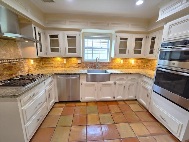 kitchen with white cabinets, sink, wall chimney exhaust hood, decorative backsplash, and appliances with stainless steel finishes