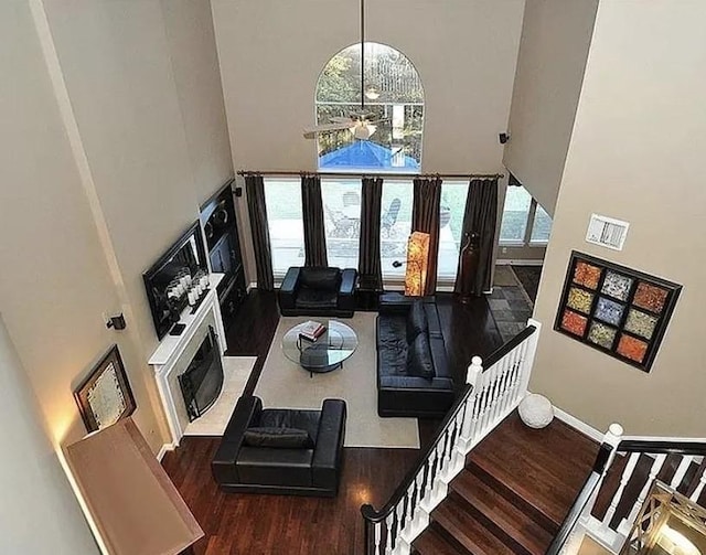 living room featuring dark wood-type flooring, a towering ceiling, and a healthy amount of sunlight