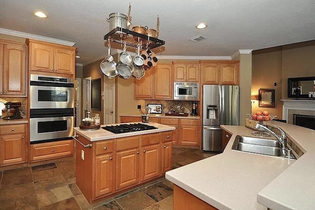 kitchen featuring sink, decorative backsplash, ornamental molding, appliances with stainless steel finishes, and a kitchen island