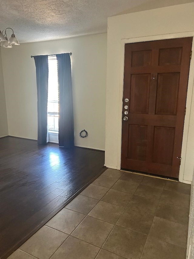 foyer with a textured ceiling, hardwood / wood-style flooring, and an inviting chandelier