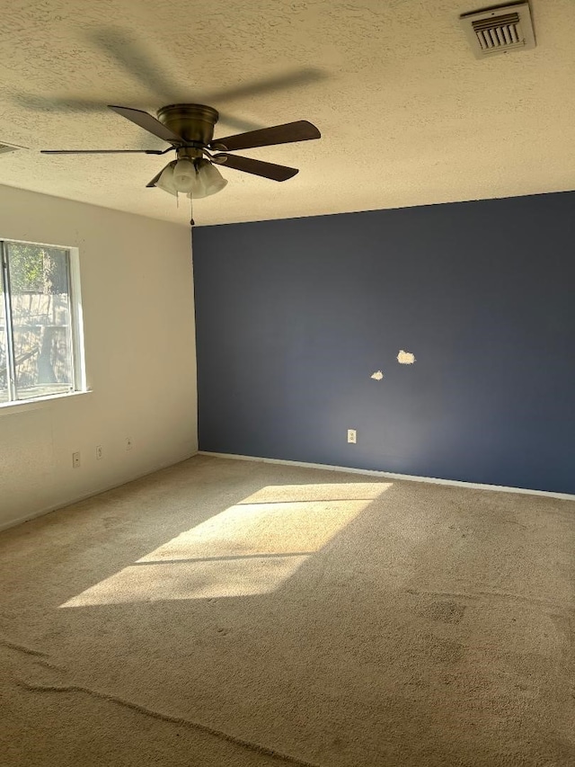 carpeted spare room featuring ceiling fan and a textured ceiling