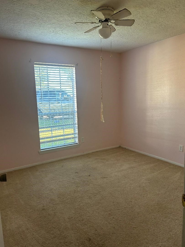 empty room featuring ceiling fan, carpet floors, and a textured ceiling