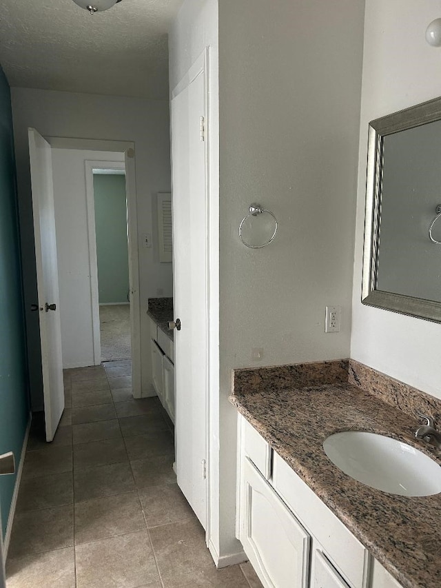 bathroom with tile patterned floors, vanity, and a textured ceiling