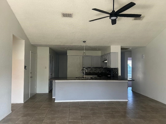 kitchen featuring sink, ceiling fan, gray cabinets, a textured ceiling, and tasteful backsplash