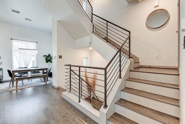 stairway featuring wood-type flooring and a towering ceiling