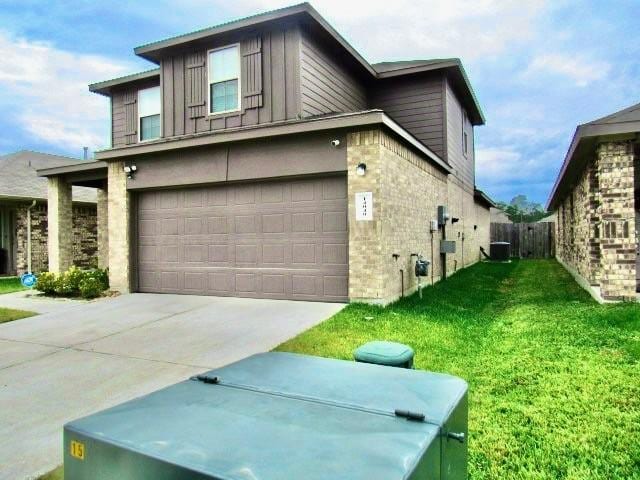 view of property exterior featuring brick siding, board and batten siding, a yard, a garage, and driveway