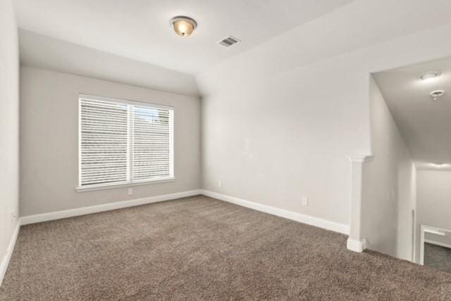 spare room with dark carpet and vaulted ceiling