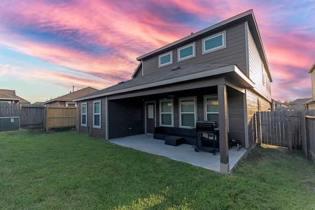 back house at dusk with a patio area and a yard