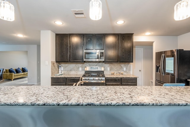 kitchen featuring backsplash, dark brown cabinets, decorative light fixtures, and appliances with stainless steel finishes