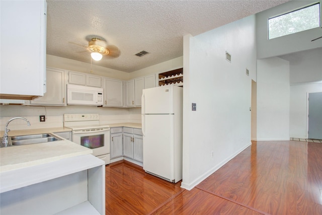 kitchen with a textured ceiling, sink, hardwood / wood-style floors, and white appliances