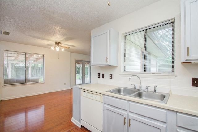 kitchen featuring light wood-type flooring, a textured ceiling, sink, dishwasher, and white cabinetry