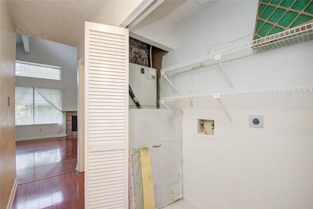 clothes washing area with hookup for a washing machine, a textured ceiling, electric dryer hookup, hardwood / wood-style flooring, and a fireplace