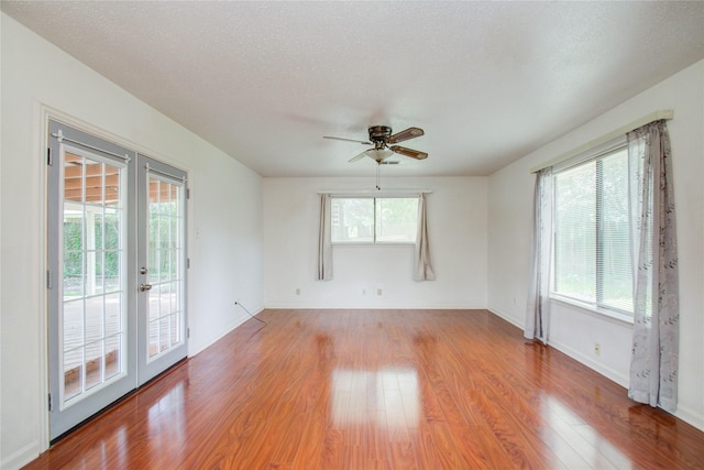 unfurnished room with ceiling fan, light hardwood / wood-style floors, a textured ceiling, and french doors