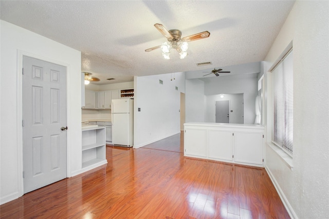 unfurnished living room with a textured ceiling and light hardwood / wood-style flooring