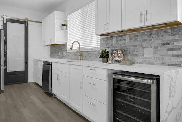 kitchen with a barn door, light hardwood / wood-style flooring, white cabinets, and wine cooler