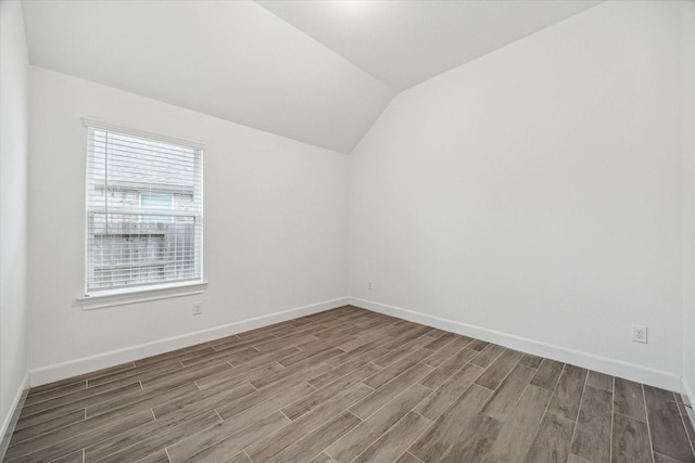 empty room featuring wood-type flooring and vaulted ceiling