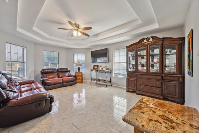 living room with plenty of natural light, ceiling fan, and a raised ceiling