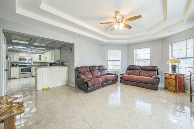 living room with ceiling fan and a raised ceiling