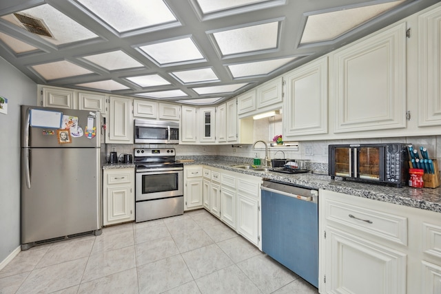 kitchen featuring coffered ceiling, sink, light stone countertops, white cabinetry, and stainless steel appliances