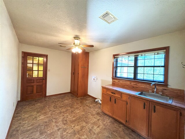 kitchen featuring ceiling fan, sink, and a textured ceiling