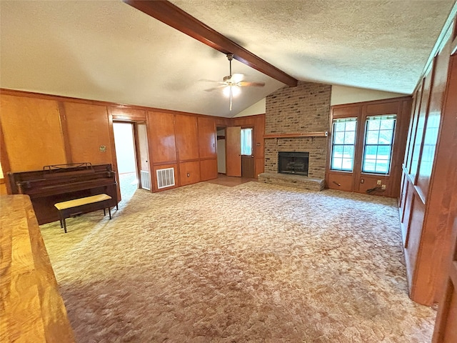 unfurnished living room featuring light carpet, lofted ceiling with beams, a brick fireplace, ceiling fan, and a textured ceiling