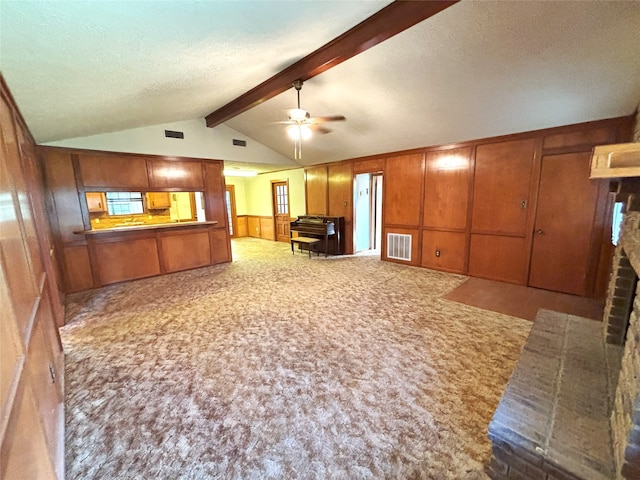 interior space featuring lofted ceiling with beams, wooden walls, ceiling fan, a textured ceiling, and carpet floors