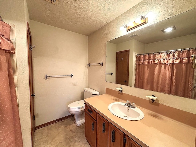 bathroom featuring vanity, a textured ceiling, and toilet