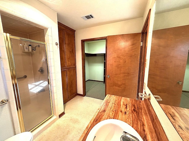 bathroom featuring a shower with door and sink