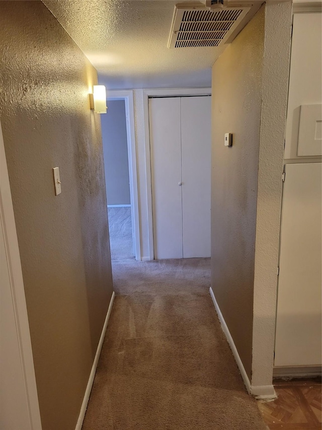 hallway featuring a textured ceiling and carpet floors