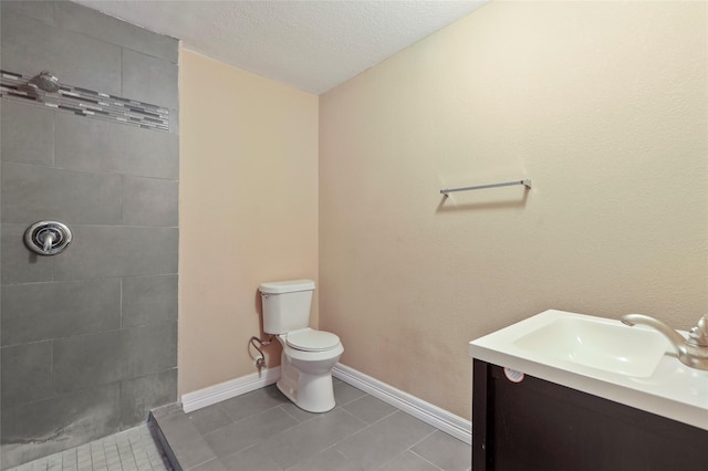 bathroom featuring toilet, vanity, a textured ceiling, and tile patterned floors