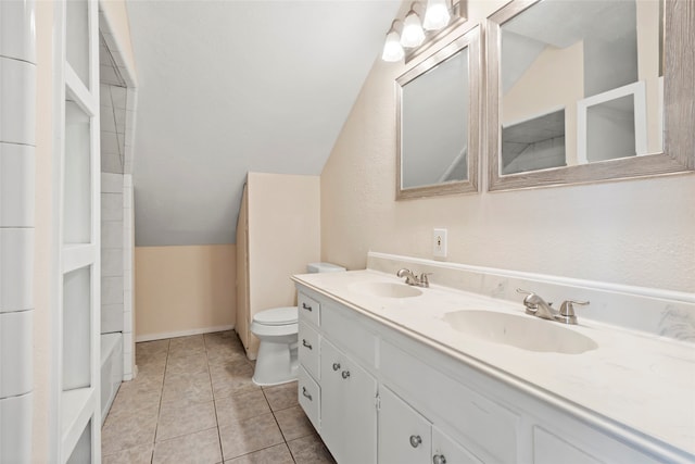 bathroom with toilet, vanity, vaulted ceiling, and tile patterned flooring