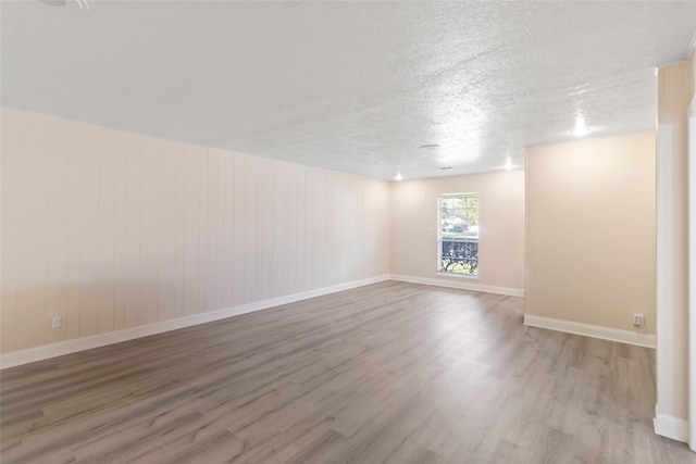 unfurnished room featuring a textured ceiling and light hardwood / wood-style flooring