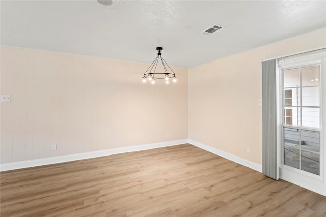 unfurnished room featuring a chandelier and light hardwood / wood-style flooring