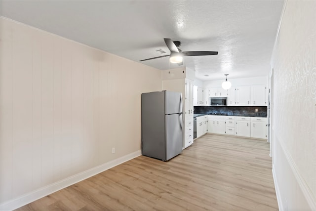 kitchen featuring white cabinets, appliances with stainless steel finishes, decorative backsplash, light wood-type flooring, and ceiling fan