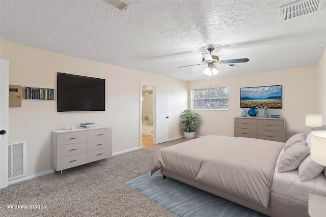 bedroom featuring ceiling fan, ensuite bath, light carpet, and a textured ceiling