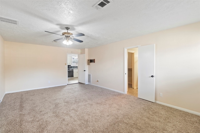 spare room with light carpet, ceiling fan, and a textured ceiling