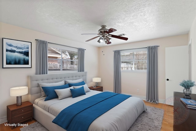 bedroom featuring ceiling fan, multiple windows, and a textured ceiling