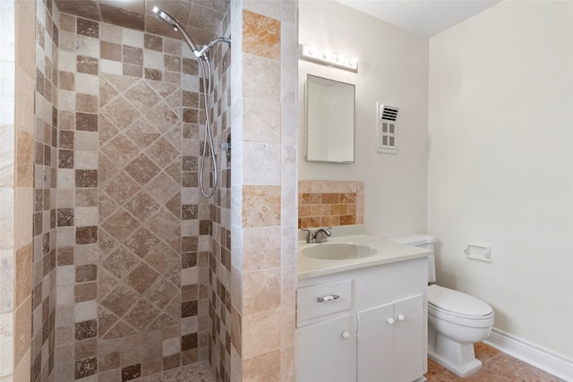 bathroom with toilet, tile patterned flooring, tiled shower, and vanity