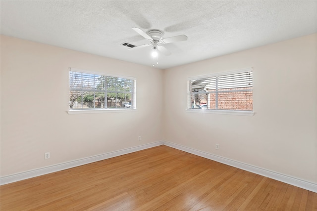 spare room featuring a textured ceiling, ceiling fan, a wealth of natural light, and hardwood / wood-style flooring