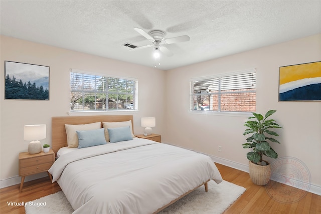 bedroom with ceiling fan, a textured ceiling, and hardwood / wood-style flooring