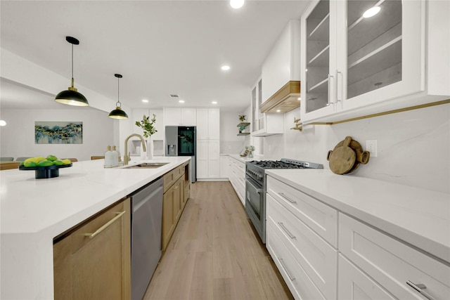 kitchen featuring pendant lighting, a large island with sink, white cabinets, appliances with stainless steel finishes, and light hardwood / wood-style floors