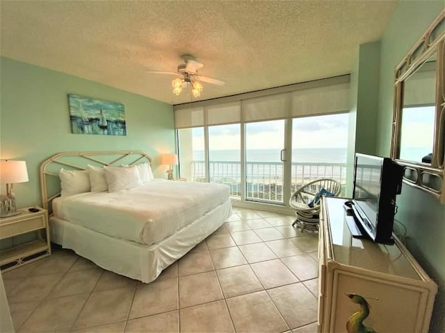 bedroom with access to exterior, ceiling fan, light tile patterned floors, and a textured ceiling