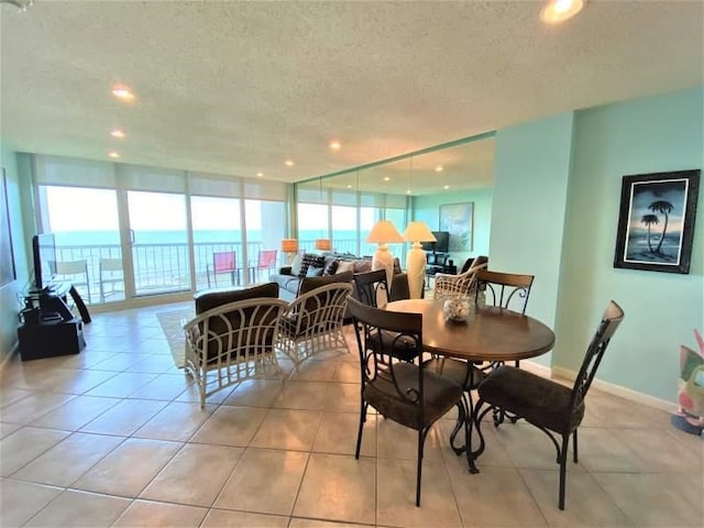 tiled dining area with a textured ceiling and floor to ceiling windows