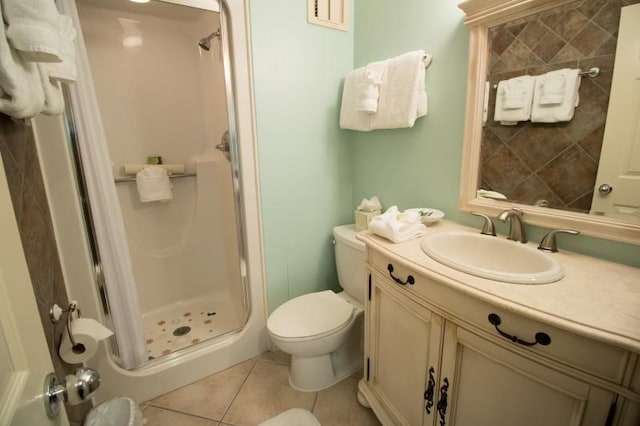 bathroom featuring a tile shower, tile patterned floors, vanity, and toilet