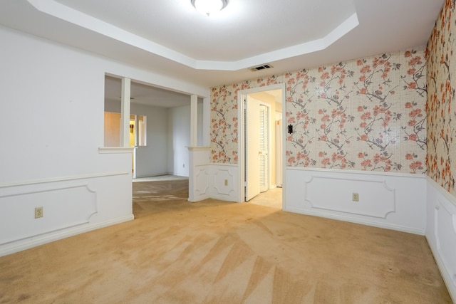 unfurnished room with a raised ceiling and light colored carpet