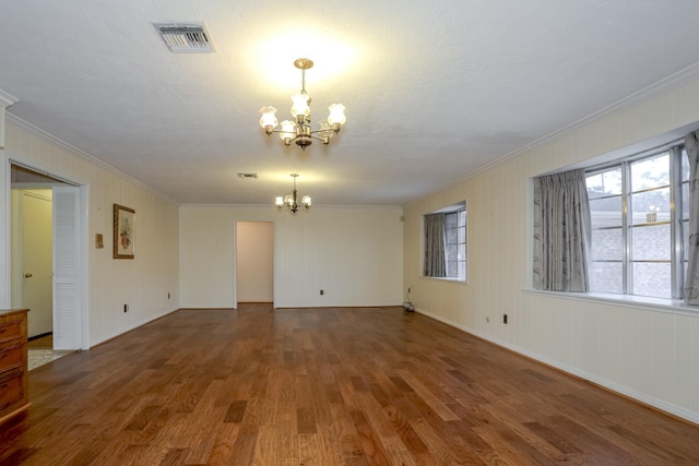 empty room featuring hardwood / wood-style flooring, ornamental molding, a textured ceiling, and a notable chandelier