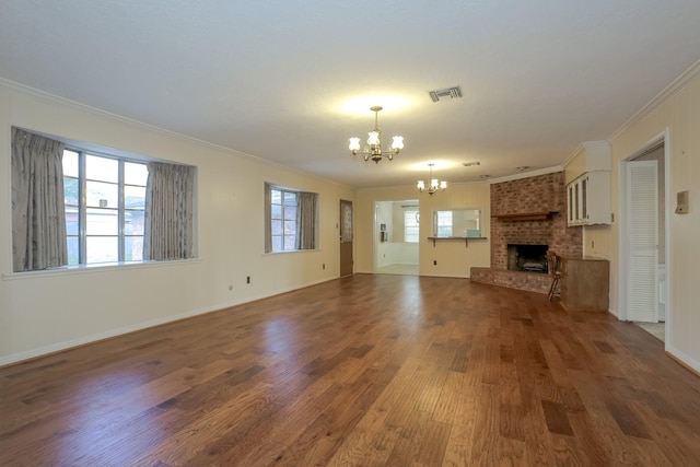 unfurnished living room featuring a brick fireplace, crown molding, a healthy amount of sunlight, and a notable chandelier