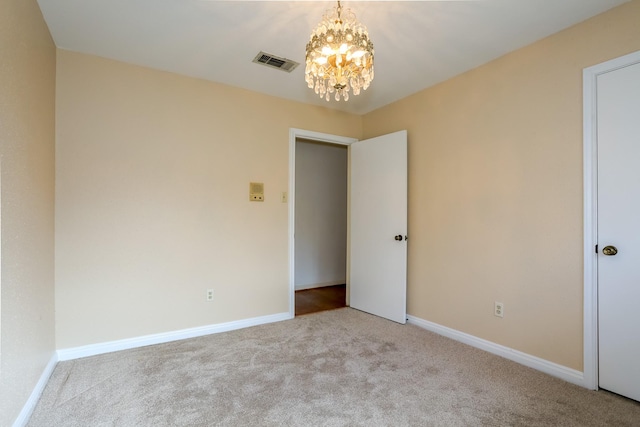 carpeted empty room featuring a chandelier