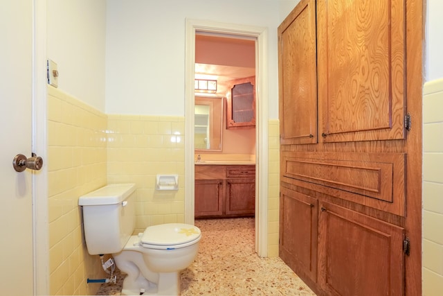 bathroom with vanity, tile walls, and toilet