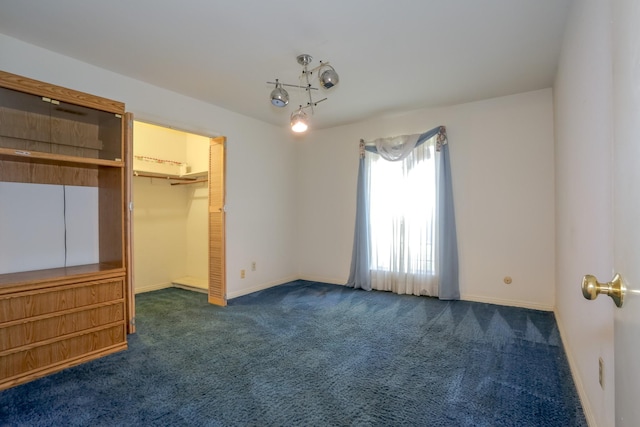 unfurnished bedroom with a walk in closet, a closet, and dark colored carpet